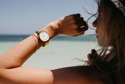 Midsection of woman on beach against sky