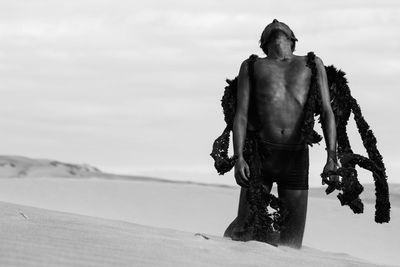 Teenage boy in costume on desert against sky