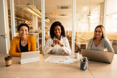 Young woman using phone while sitting on table