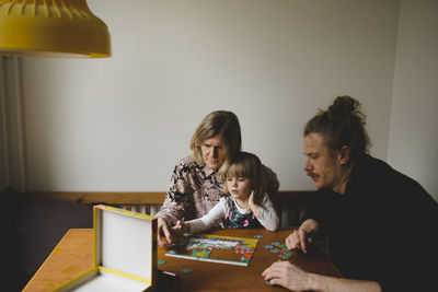 Grandparents and granddaughter doing puzzles