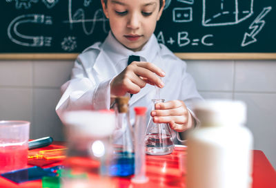 Boy wearing lap coat while sitting in classroom