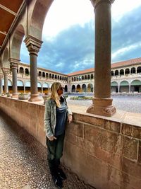 Rear view of woman standing in front of historical building