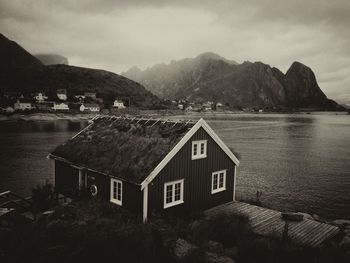 Houses by lake and mountains against sky