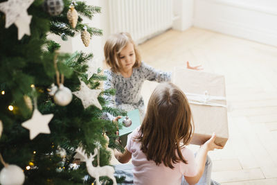 Mother and girl on christmas tree at home