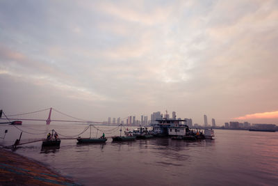 Boats in sea against cloudy sky