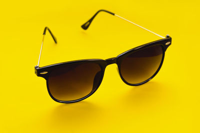 Close-up of sunglasses over yellow background