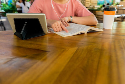 Midsection of woman using mobile phone while sitting on table