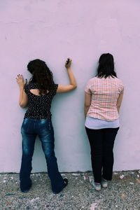 Rear view of woman standing against wall