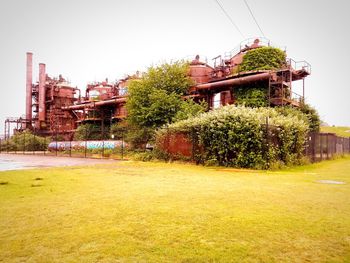 Plants growing on field by building against clear sky