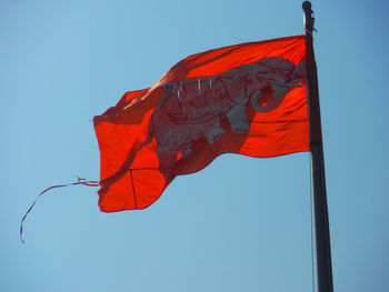 Low angle view of red flag against blue sky