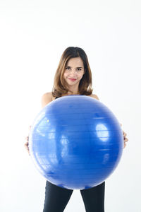 Portrait of woman holding ball against white background