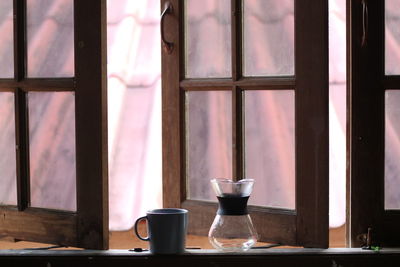 Close-up of coffee cup on window sill at home