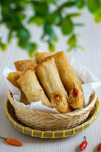 Lumpia in basket on wooden table