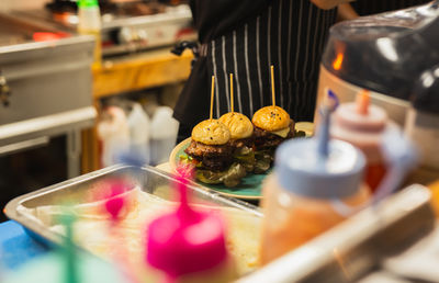 Hamburger being prepared in the kitchen with green salad.