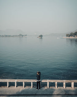 Rear view of man looking at sea against sky