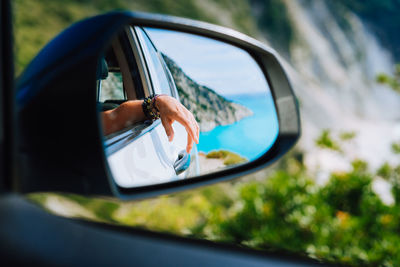 Reflection of man on car side-view mirror