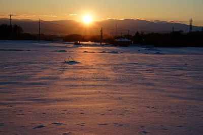 Scenic view of snow covered field during sunset