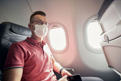 Portrait of passenger with protective face mask in airplane.