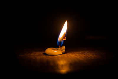 Close-up of illuminated candle in darkroom