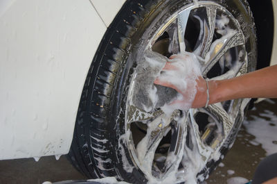 Cropped image of mechanic washing car wheel in garage