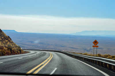 Empty road leading towards mountains against sky near arizona.