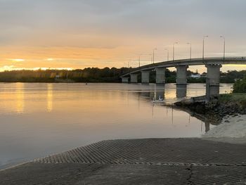 Bridge over river against sky during sunset