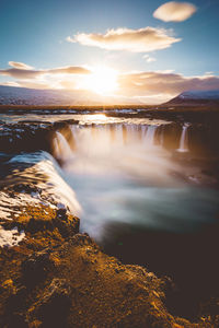 Scenic view of waterfall against sky during sunset