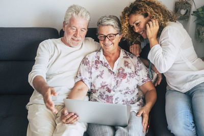 High angle view of family using laptop while sitting on sofa