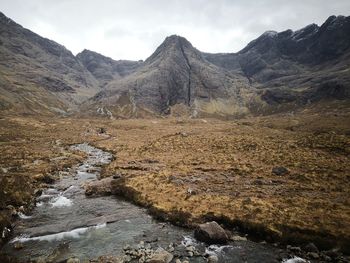 Scenic view of stream by mountains against sky