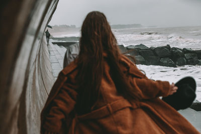 Rear view of woman looking at sea shore against sky