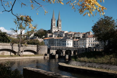 Arch bridge over river by buildings against clear sky