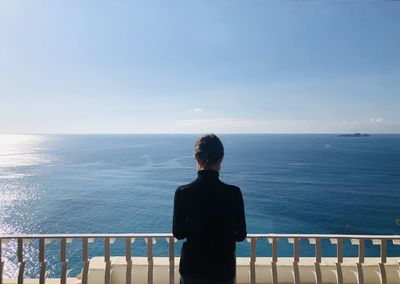 Rear view of man looking at sea against sky