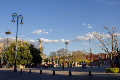 People on street in city against sky