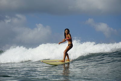 Full length of beautiful woman surfing in sea