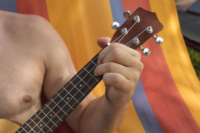 Midsection of man playing guitar