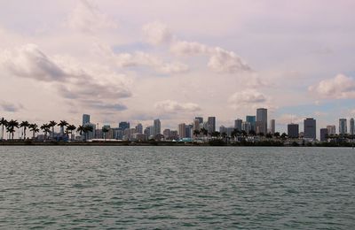 Sea and buildings in city against sky