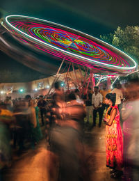 People in amusement park ride at night