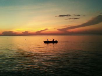 Silhouette people in boat on sea against sky during sunset