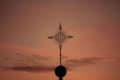 Low angle view of weather vane against sky