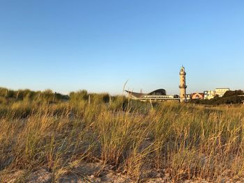 Lighthouse on field against clear blue sky