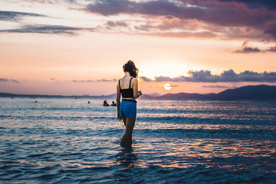 Rear view of woman at beach during sunset
