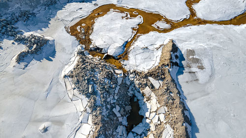 The ice has broken as snow melts at the quarry forming a small stream in the dirt.