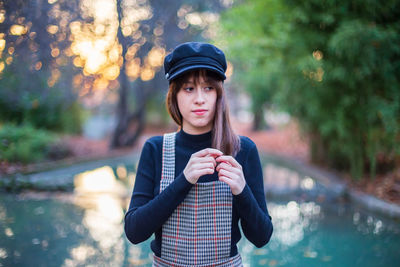 Portrait of beautiful young woman standing against trees