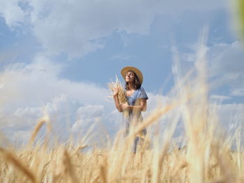 Rear view of woman standing on field against sky