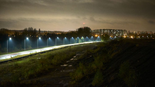 Illuminated bridge over river against sky at night