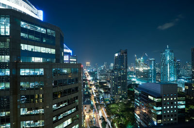 Aerial view of illuminated buildings in city against sky at night