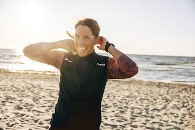 Happy female coach laughing while standing at beach