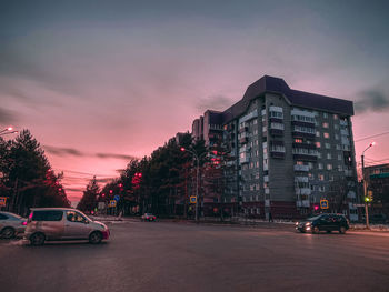 Cars on road against sky at sunset