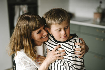 Happy mother embracing son with disability at home