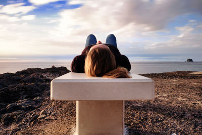 Rear view of woman sitting on beach